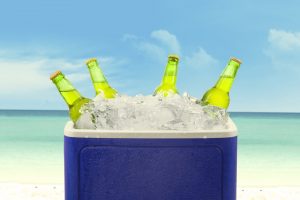Closeup of an ice chest full of ice and assorted beer bottles.